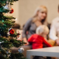man and woman sitting at a table with their young child by a christmas tree