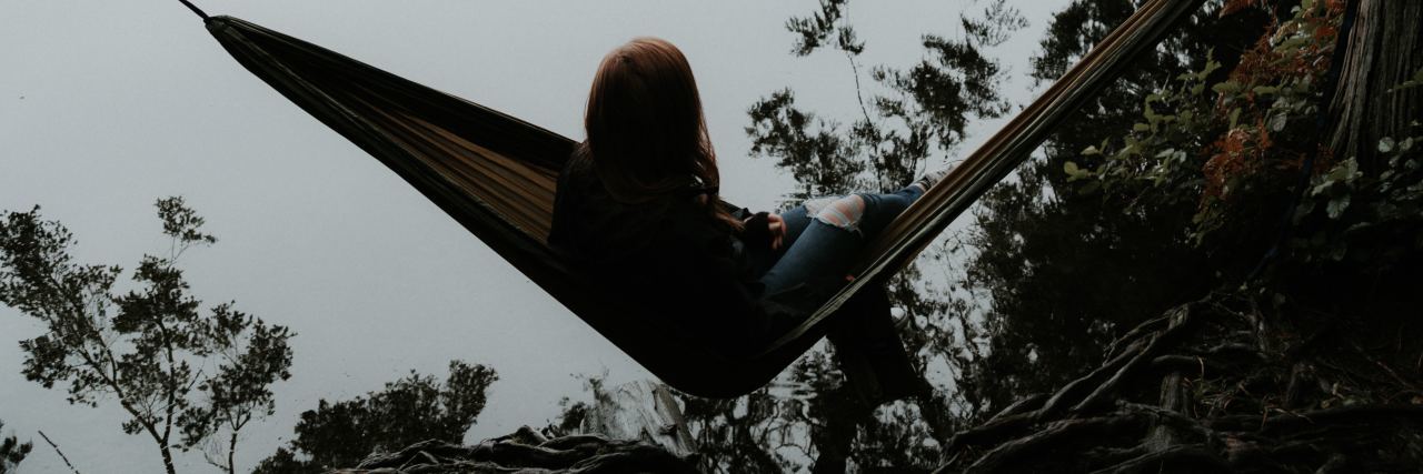 woman sitting on hammock in front of misty lake