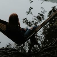 woman sitting on hammock in front of misty lake