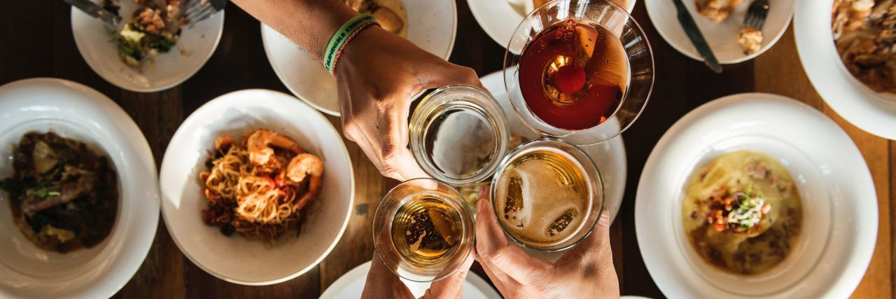 people clinking glasses over a dinner table