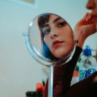 woman looking into circular mirror