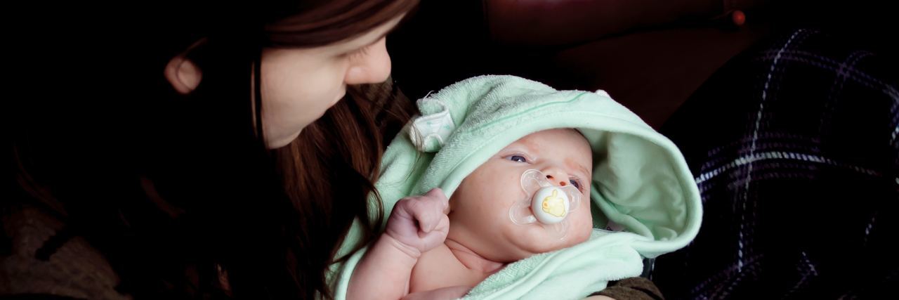 Why Postpartum OCD Is When You're Scared You Want to Hurt Your Baby mother holding baby wrapped in towel with unknown expression