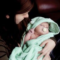 mother holding baby wrapped in towel with unknown expression