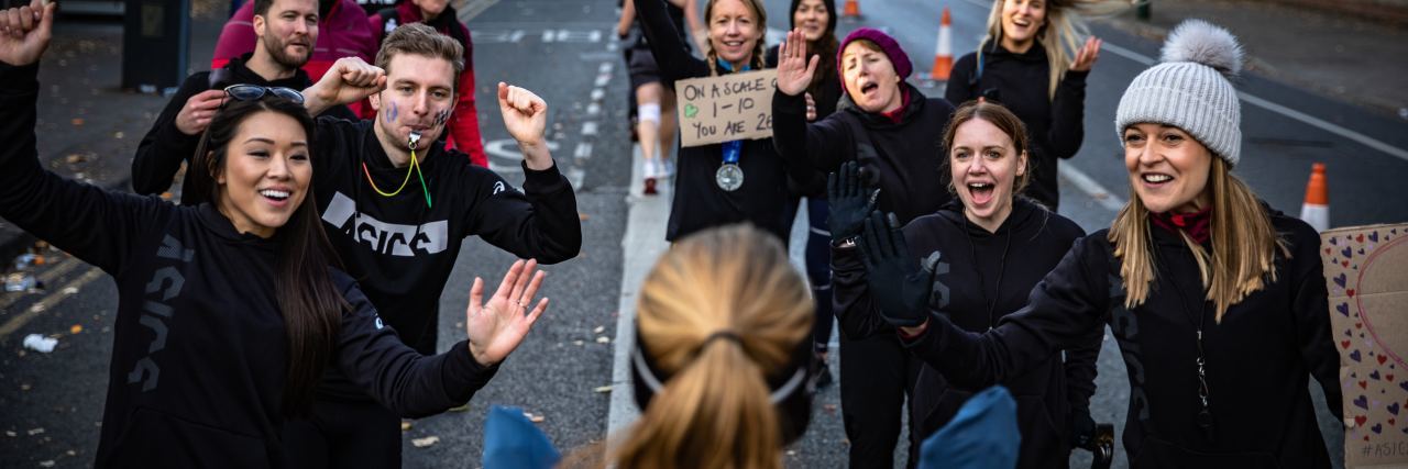 What Running a Half-Marathon Reminded Me About Mental Health Recovery woman finishing marathon with people waiting for her