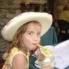 Julia at age 5, wearing a big hat and eating ice cream.