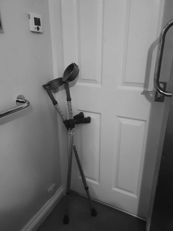 forearm crutches standing in the corner of a room by a door