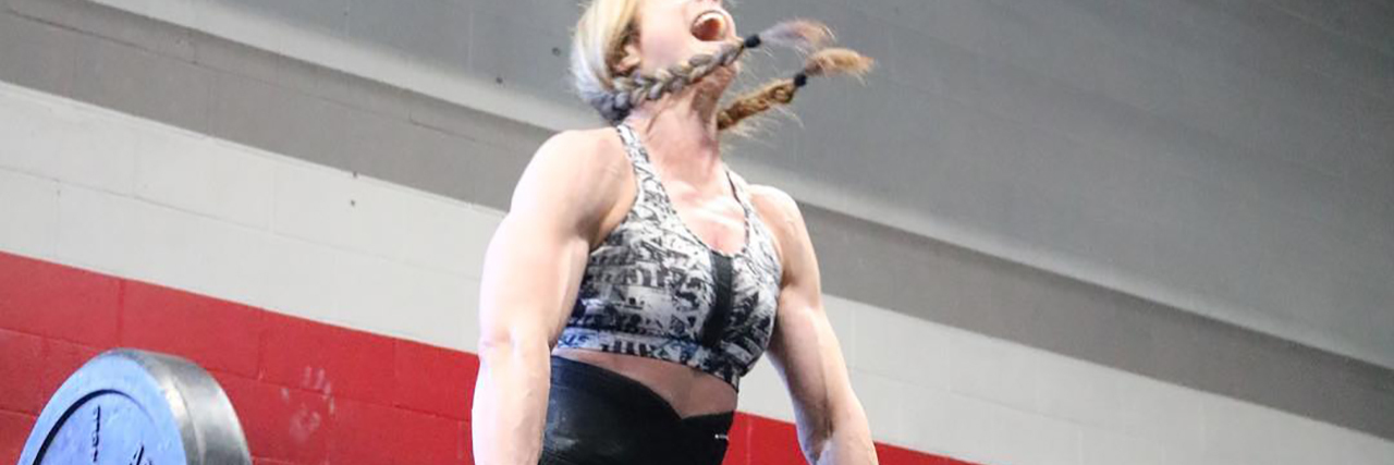 photo of contributor woman shouting while raising weight lifting bar