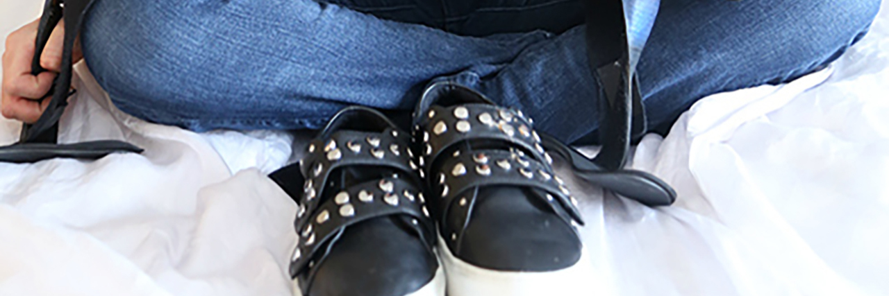 DIY Adaptive Fashion for People With Disabilities Lainie Ishbia holding her AFOS with a pair of adapted shoes sitting in front of her.