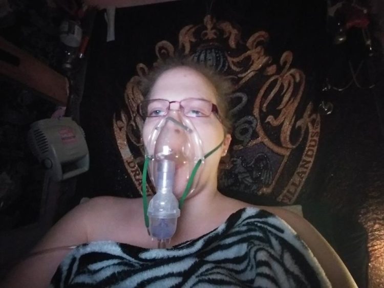 woman lying down with a zebra blanket across her. she has an oxygen mask strapped to her face
