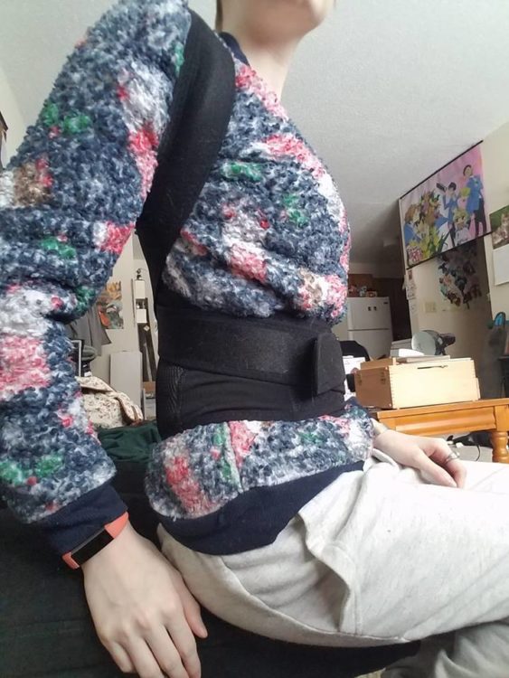 woman wearing black brace to support her back over her shirt and pants