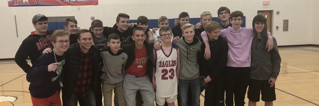 Inclusion Through Sports for My Son With Down Syndrome Alex wearing his basketball uniform surrounded by his soccer team friends