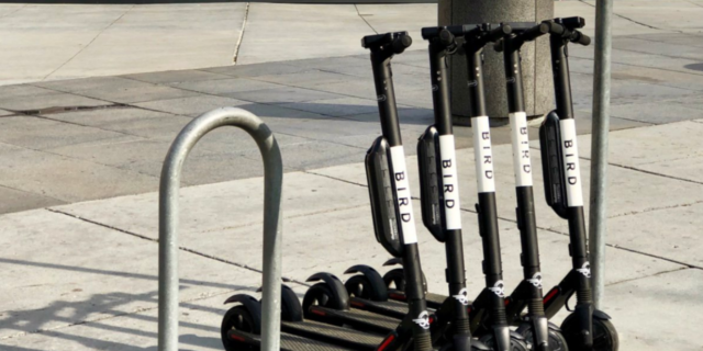 Motor Scooter Companies, San Diego Are Violating the Americans With Disabilities Act, Lawsuit Claims A row of bird scooters parked near a bike rack.