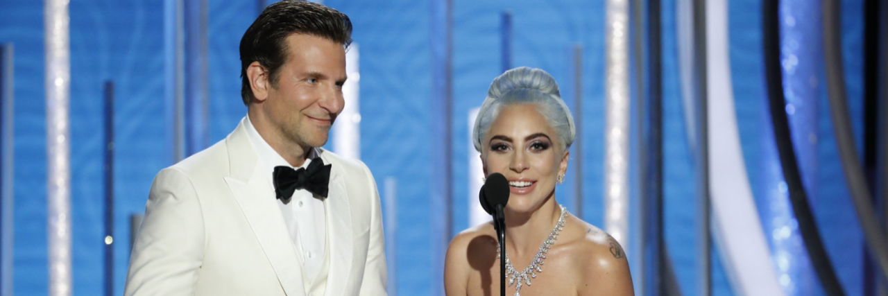 Bradley Cooper in a white tux and Lady Gaga in a light blue gown on the stage at the Golden Globes