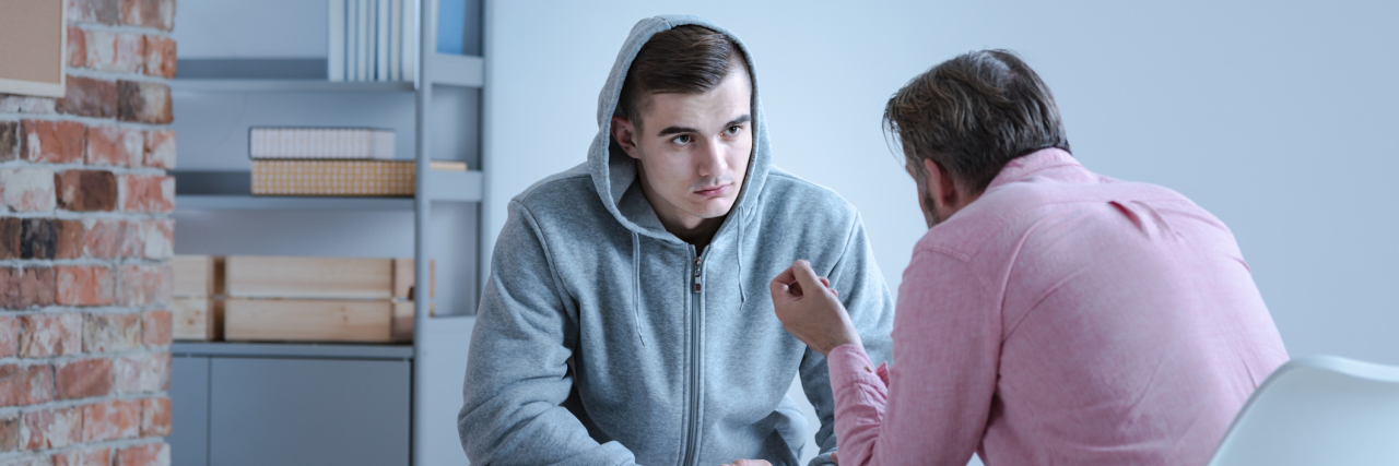 A psychology specialist explaining an action plan for recovery to a teenage boy during an individual therapy session.