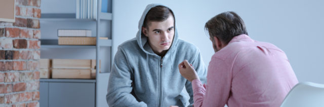 A psychology specialist explaining an action plan for recovery to a teenage boy during an individual therapy session.