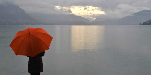 Why I Prefer the Cloudy Days With Porphyria  girl with umbrella facing a lake and clouds in the sky