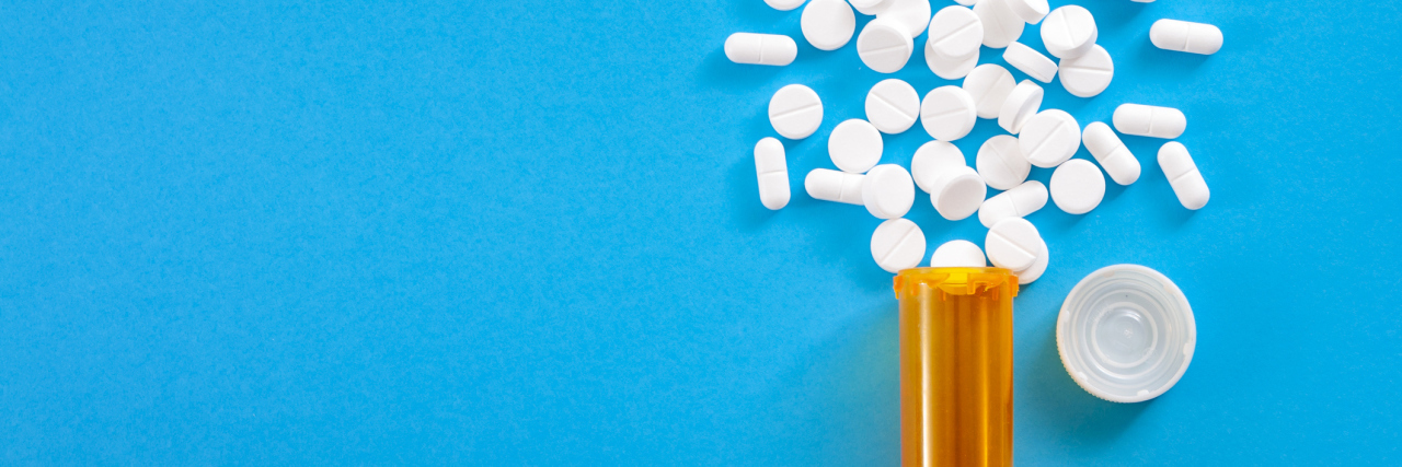 I Take Psychiatric Medication to Feel OK, and That's OK Medicine, opioid painkillers and prescription medicines concept with top view of orange prescription bottle of oxycodone and hydrocodone pills spilled on a blue background with copy space