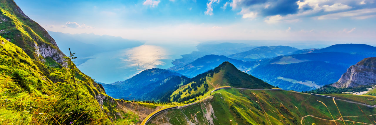 Traveling While Living With Chronic Pain Scenic summer panorama from Rochers de Naye mountain peak with green grassy hills, flower meadows and Geneva Lake in Alps, Switzerland.