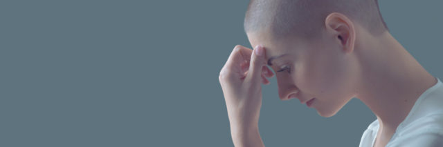 photo of woman with shaved head looking sad or thoughtful with hand to brow