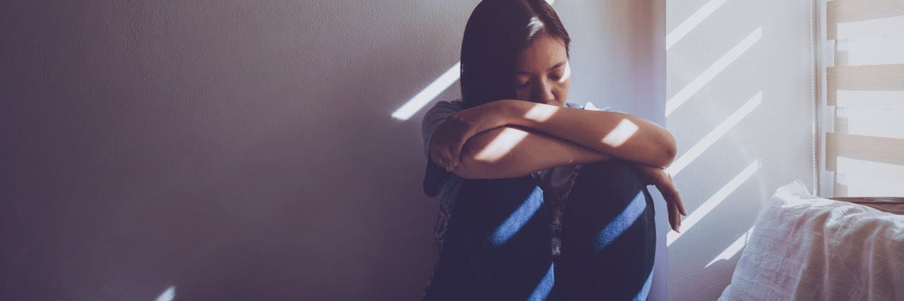 What It's Like to Live With ADHD as an Adult Woman a girl sitting and hugging her knees