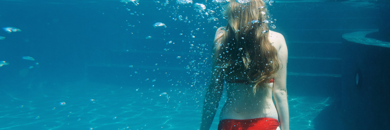 What Emptiness Feels Like A woman in a red bikini floating underwater in a pool
