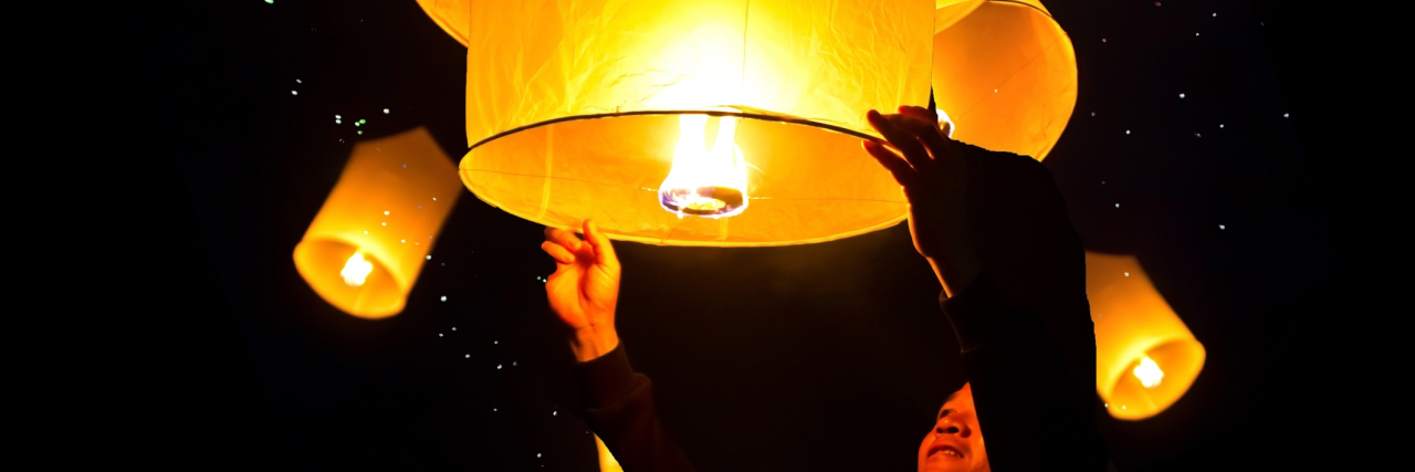 Finding Blessings in Chronic Illness: Hope for a New Year person holding floating lantern at night