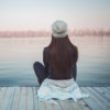 Girl sitting on pier and looking at river
