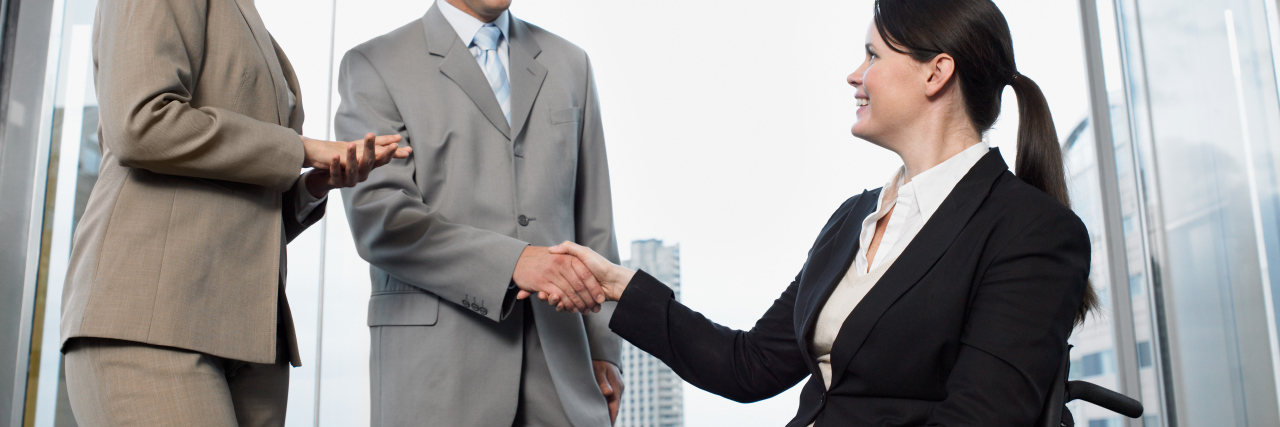 Improving Opportunities for Disabled Workers Office worker in a wheelchair shaking hands with colleague.