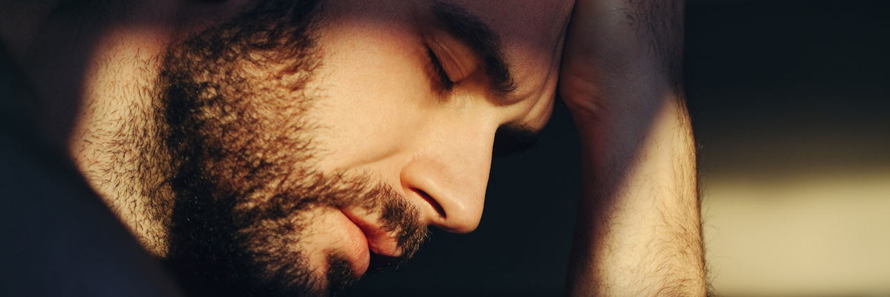 How Mental Health Stigma Hurts People in Recovery Man sitting in the dark, closing his eyes