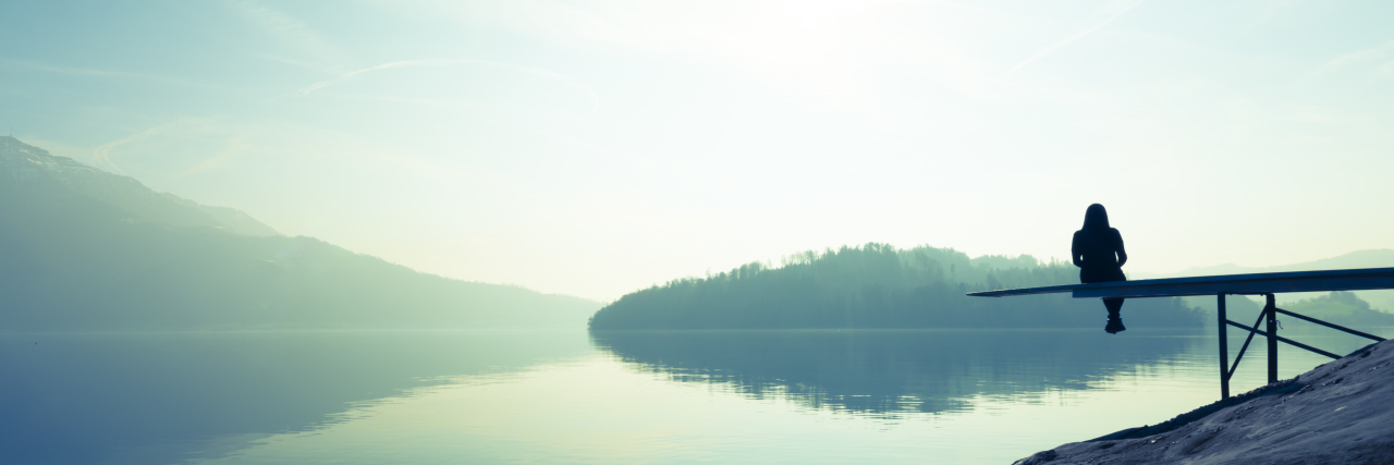 Woman sitting alone on the shore of the lake.