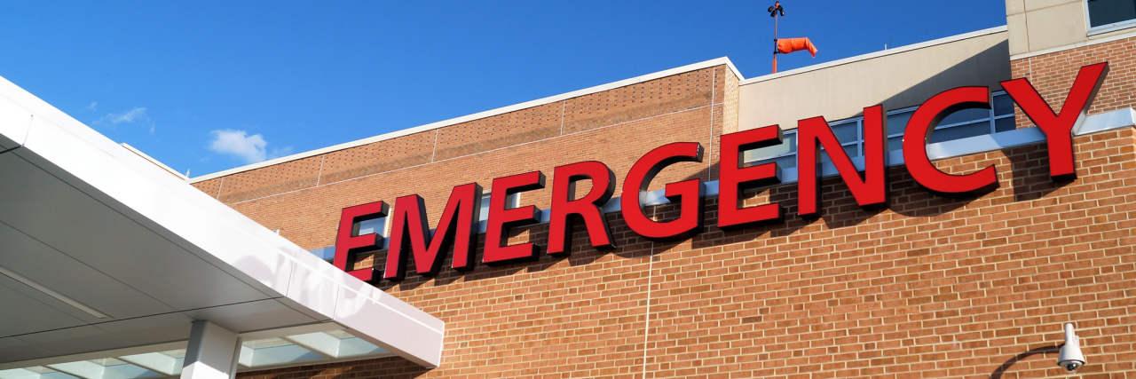 A red Emergency sign marks the entrance of a hospital emergency department