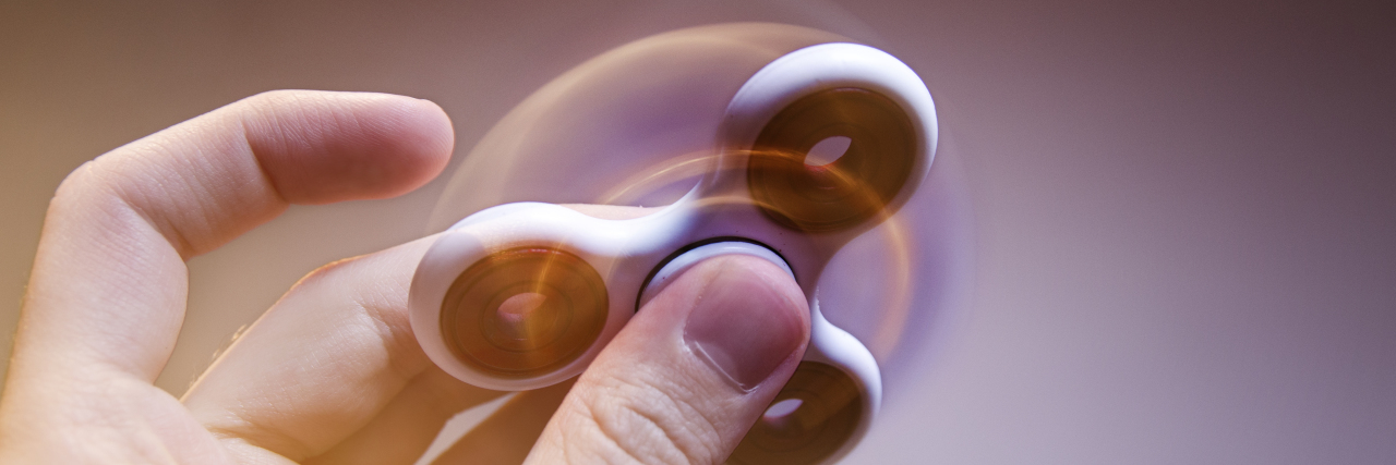 The Importance of Stimming for Autistic People Motion blur and glow fidget spinner closeup.