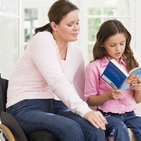Woman in wheelchair reading with child.