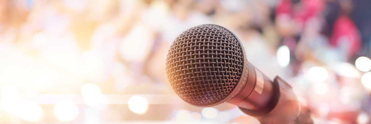 The 5 Greatest Decisions I Made as a Man With Autism Microphone on stage in concert with people in background.