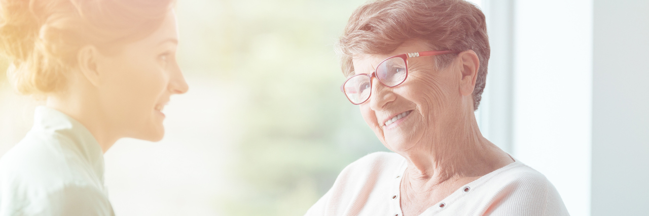 4 Lessons I Learned Volunteering for Someone With Alzheimer's Disease Young volunteer holding hands of smiling elderly woman in wheelchair