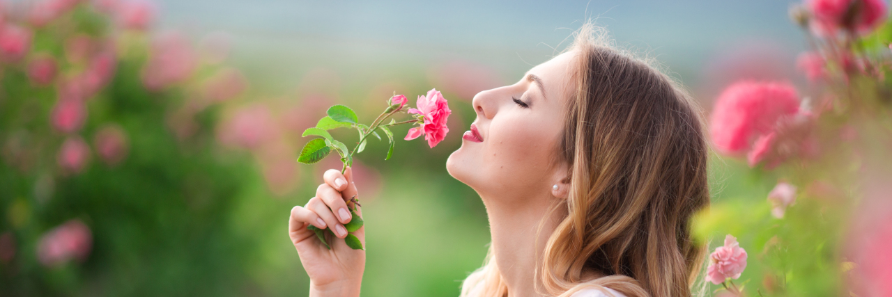 Woman stopping to small the roses.