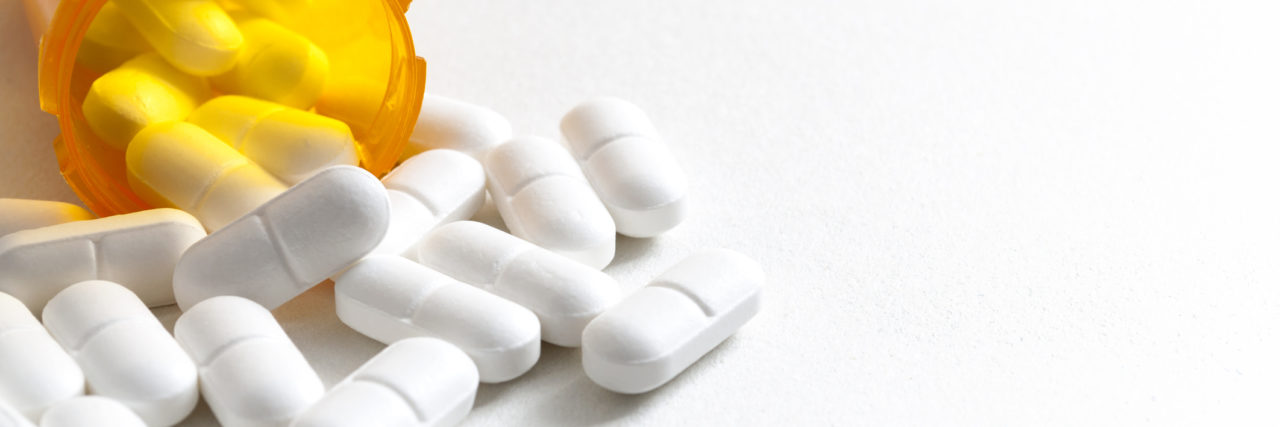 When You're Still Mentally Unstable on Psychiatric Medication Opioid epidemic, drug abuse and overdose concept with scattered prescription opioids spilling from orange bottle with copy space. Hydrocodone is the generic name for a range of opiate painkillers