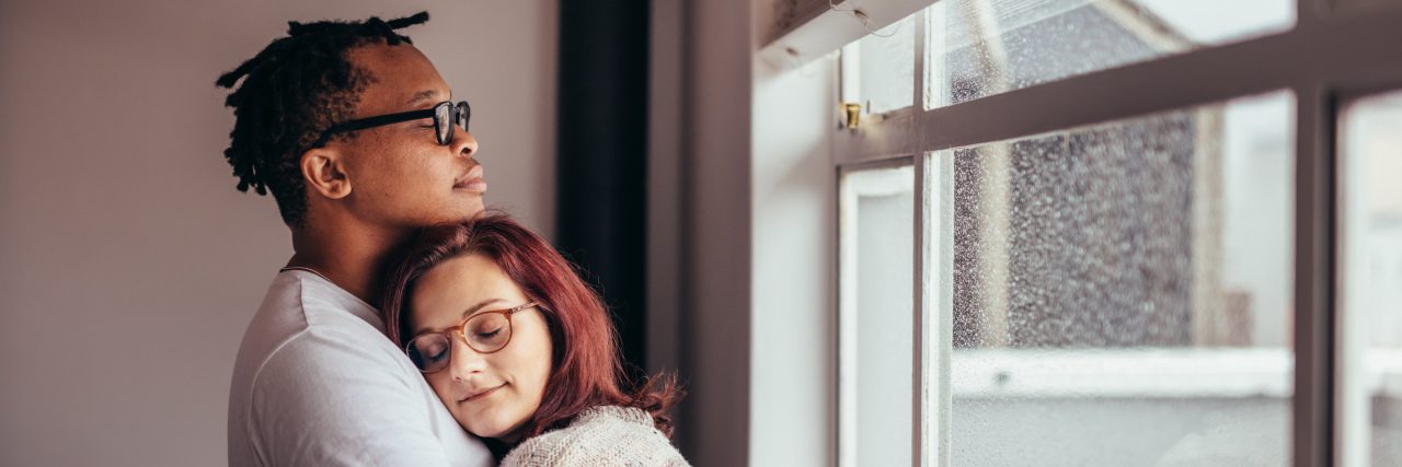 How to Talk to Your Lover About Your Disability Interracial couple hugging near window.