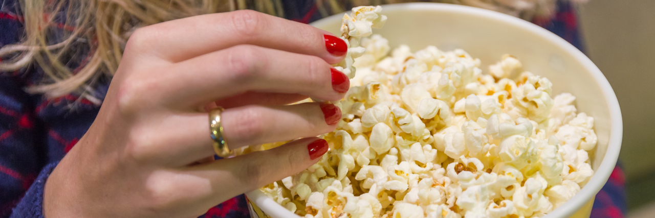 Woman's hand close up, picking up popcorn.
