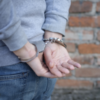 Close up of man's hands handcuffed behind his back in front of a brick wall.