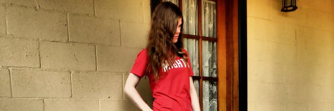 Jess standing with a cane, wearing her Mighty t-shirt.