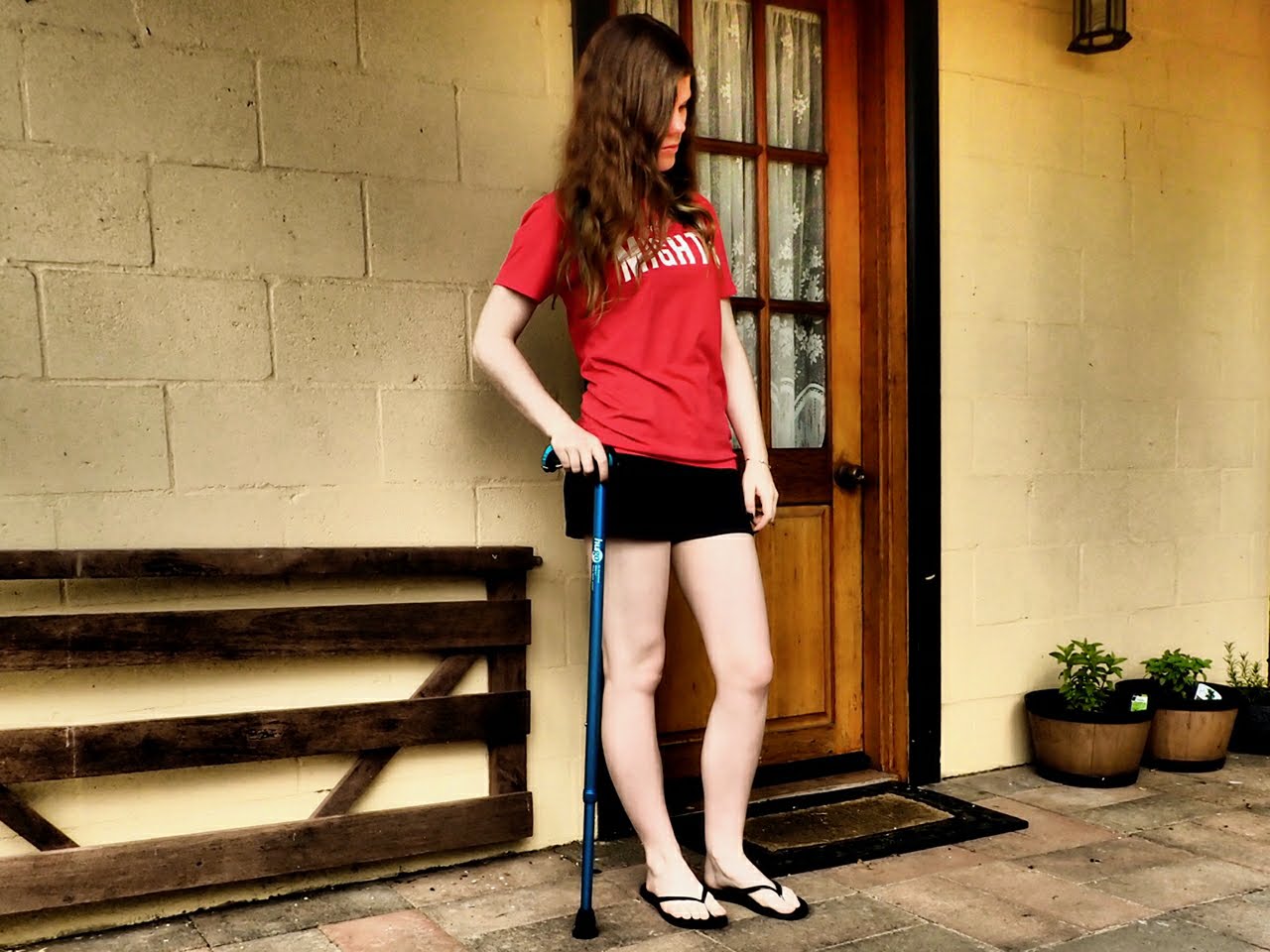 Jess standing with a cane, wearing her Mighty t-shirt.