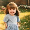 Sarah Rupp McKee as a child, standing outside wearing a blue dress.