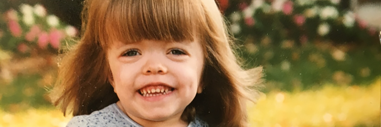 Achondroplasia Doesn't Need a Cure Sarah Rupp McKee as a child, standing outside wearing a blue dress.