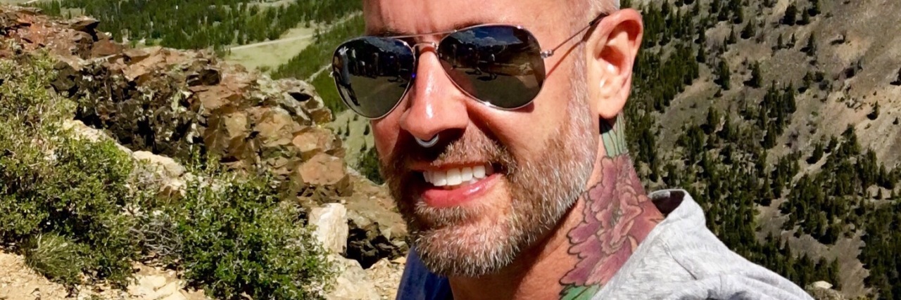 How to Have Hope as a Gay Man With Addiction and HIV photo of man with tattoos wearing sunglasses and posing in front of desert