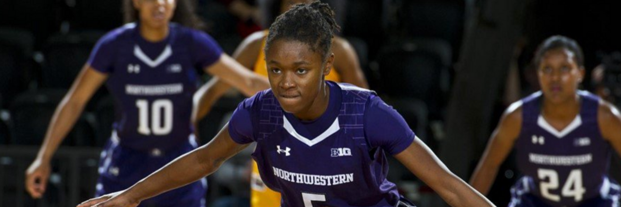 Jordan Hankins in her purple Northwestern basketball gear on the court. Her arms are spread out anticipating her next move in the game.