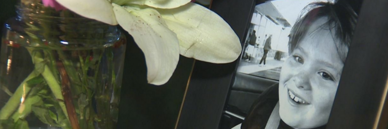 Guiding Hands School Forced to Close Six Weeks After Student's Death Black and white framed photo of Max Benson smiling next to a vase of flowers.