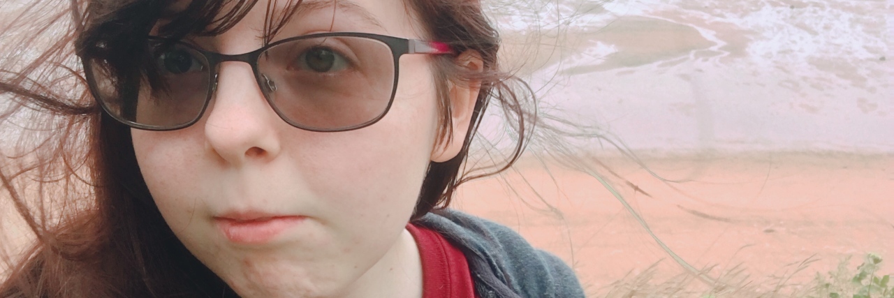 My Autism Went Undiagnosed Because I'm Female Taylor standing outside with a field in the background.