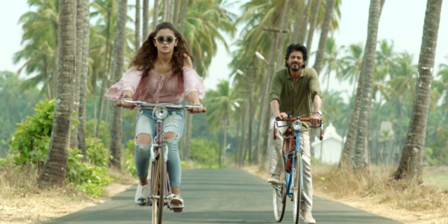 How This Bollywood Movie Is Challenging Mental Health Stigma in India still image of bollywood movie Dear Zindagi showing male and female actors riding down tree-lined road on bicycles