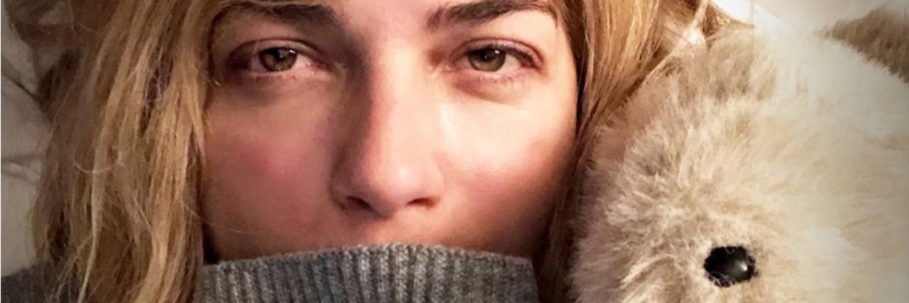 Selma Blair Posts on Instagram About Anxiety and Chronic Illness Selma Blair laying in bed with a teddy bear.